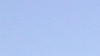 Traktor auf Feld mit grünem Bewuchs unter blauem Himmel. (automatisch generiert durch KI)