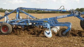 Ein blauer Lemken-Pflug bearbeitet ein Feld unter einem bewölkten Himmel. (automatisch generiert durch KI)